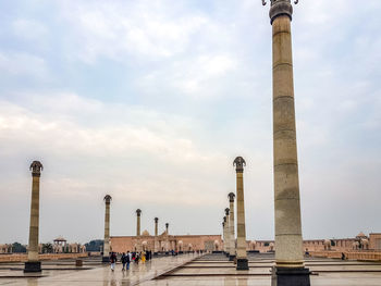 People walking in front of historical building against sky
