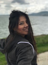 Portrait of smiling young woman against sea