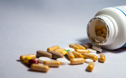 Close-up of medicines spilling from bottle on table