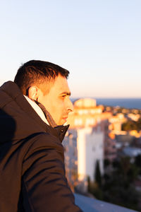 Side view of young man standing against sea