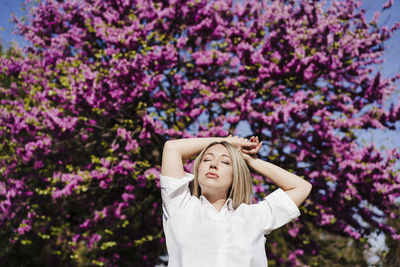 Portrait of a teenage girl standing against purple flowers