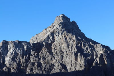 Low angle view of rocky mountains against clear blue sky