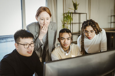 Multiracial programmers brainstorming over computer in creative office