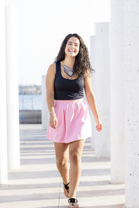 Portrait of a smiling young woman standing against wall