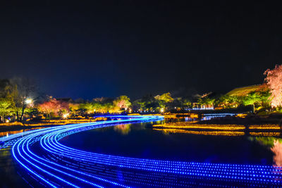 Illuminated light trails in city against sky at night