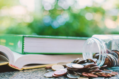 Close-up of coins spilling from jar on table