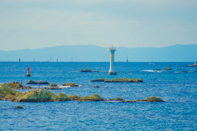 Lighthouse by sea against sky