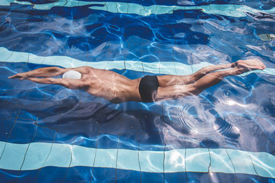 Low section of man swimming in pool