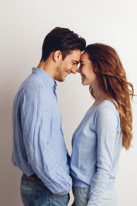 Happy young couple standing face to face in front of white background