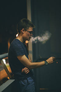 Side view of man smoking in balcony at night