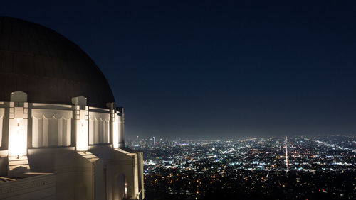 Illuminated city against blue sky at night