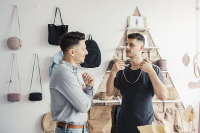 Male entrepreneur showing chain to customer in design studio