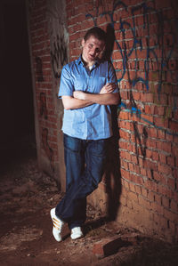 Portrait of man standing against brick wall