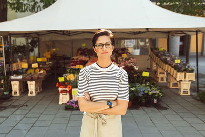 Portrait of confident female owner standing arms crossed outside flower shop