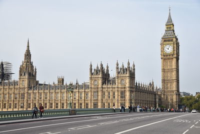 Road by big ben in city against sky