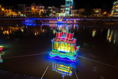 Illuminated buildings by river in city at night soc trang