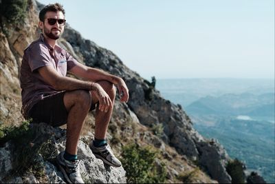 Full length of young man sitting on rock