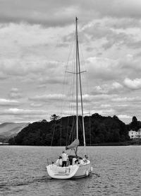 Sailboat sailing in sea against cloudy sky