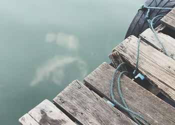 Close-up of rope tied on boat moored in lake against sky