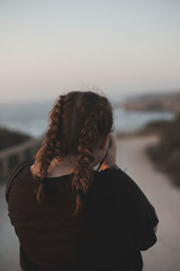 Rear view of woman standing at beach during sunset