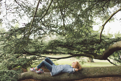 Woman lying on tree trunk at park