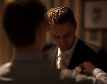 Rear view of groomsman adjusting napkin for bridegroom