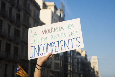 Low section of person holding text against building in city