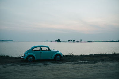 Vintage car on sea shore against sky