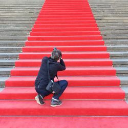Rear view of a male paparazzi on red carpeted stairs