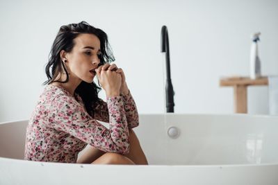 Woman looking away while sitting in bathtub