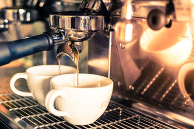 Close-up of machinery pouring coffee in cup at cafe