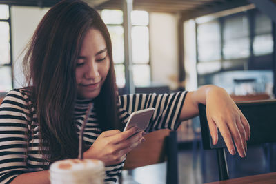 Woman using mobile phone in cafe