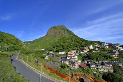 High angle view of houses and mountains against blue sky