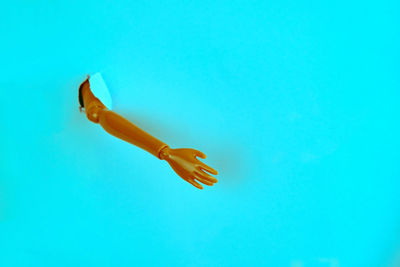 Close-up of figurine hand coming out from blue background