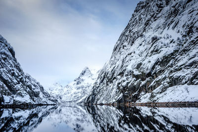 Scenic view of calm lake by snowcapped mountain against sky