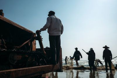 Rear view of people walking on beach