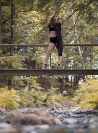 Woman standing by trees in forest