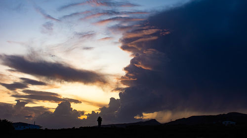 Scenic view of dramatic sky over silhouette land