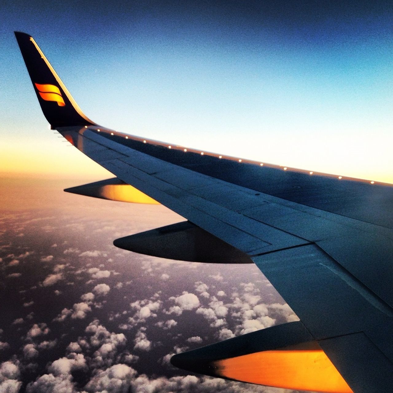 airplane, aircraft wing, transportation, air vehicle, flying, mode of transport, part of, cropped, mid-air, travel, sky, aerial view, journey, public transportation, on the move, sunset, airplane wing, vehicle part, outdoors, no people