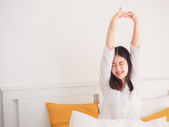 Beautiful young woman relaxing on bed against wall at home