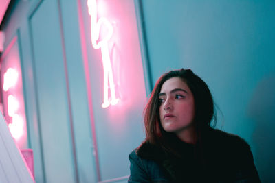 Portrait of beautiful young woman against wall