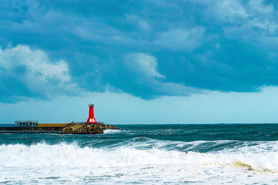 Lighthouse by sea against sky