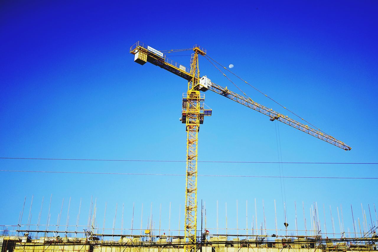 clear sky, blue, low angle view, fuel and power generation, technology, electricity pylon, copy space, power supply, power line, electricity, crane - construction machinery, construction site, day, outdoors, built structure, development, no people, construction, building exterior, crane