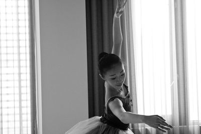 Young woman standing against window at home