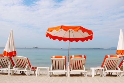 Deck chairs and parasols on beach against sky