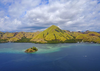 Scenic view of sea by mountain against sky