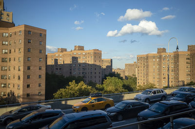 Traffic on road by buildings against sky