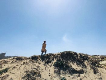 Man standing on rock against sky