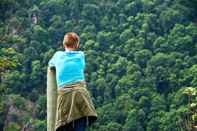 Rear view of man standing against trees in forest