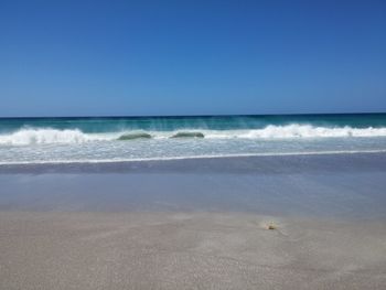 Scenic view of beach against clear blue sky